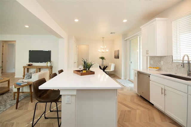 kitchen featuring dishwasher, a kitchen island, sink, and white cabinets