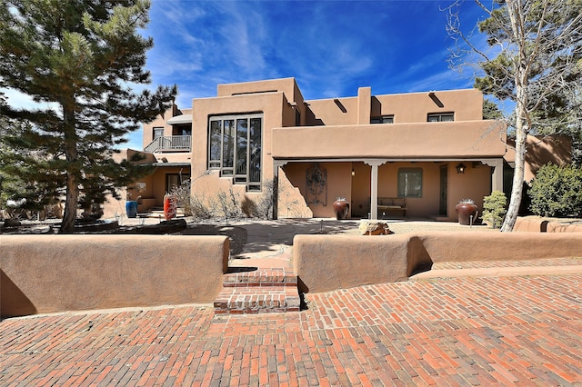 pueblo revival-style home featuring stucco siding and a balcony