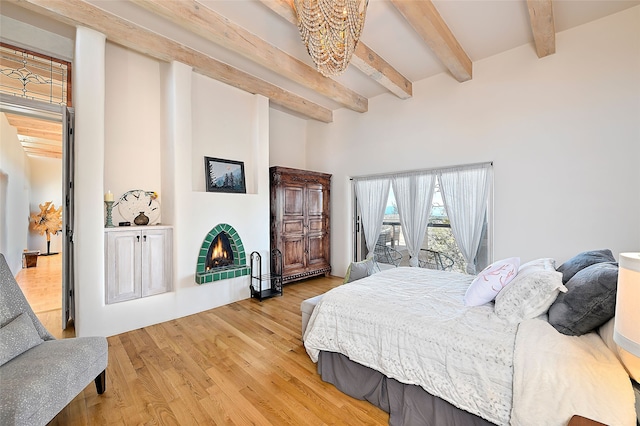 145 Brownell Howland, Santa Fe, NM 87501 - bedroom with a chandelier, beamed ceiling, wood finished floors, and a warm lit fireplace
