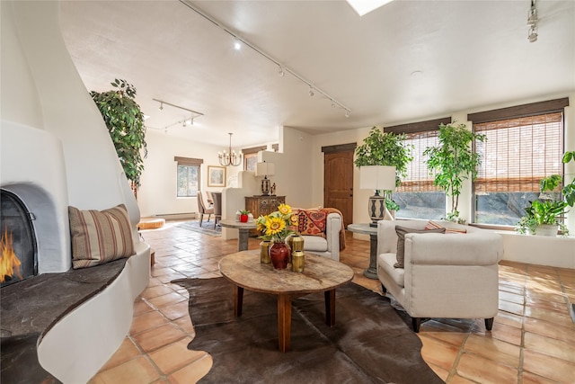 living room featuring an inviting chandelier, rail lighting, light tile patterned flooring, and baseboard heating