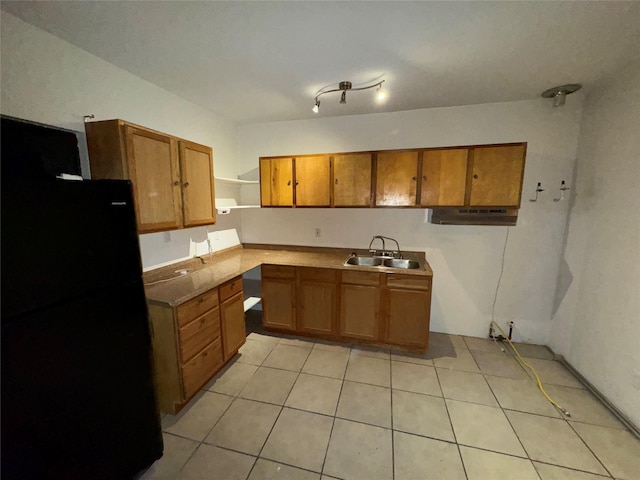 kitchen with light tile patterned floors, a sink, freestanding refrigerator, brown cabinets, and open shelves