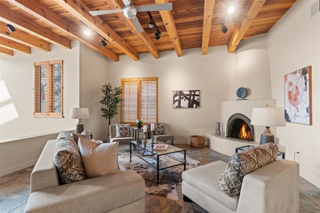 living room with ceiling fan, a large fireplace, wood ceiling, and beam ceiling