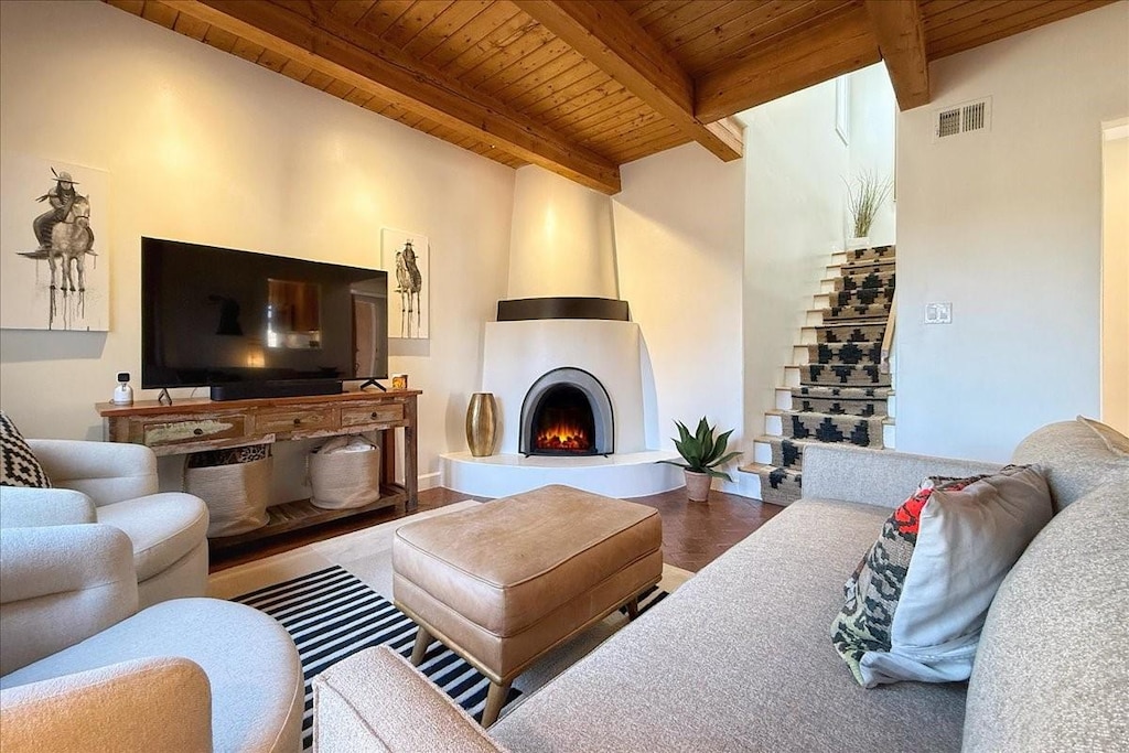 living room with beam ceiling, wood-type flooring, wooden ceiling, and a fireplace