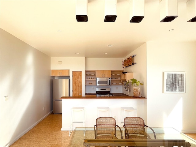 kitchen with stainless steel appliances, a breakfast bar area, and kitchen peninsula