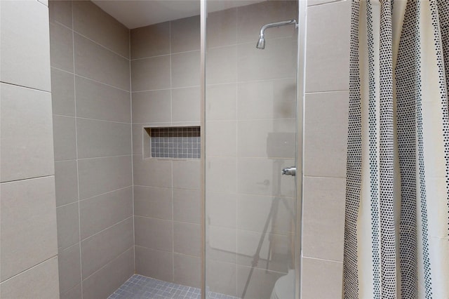 bathroom with a tile shower and toilet