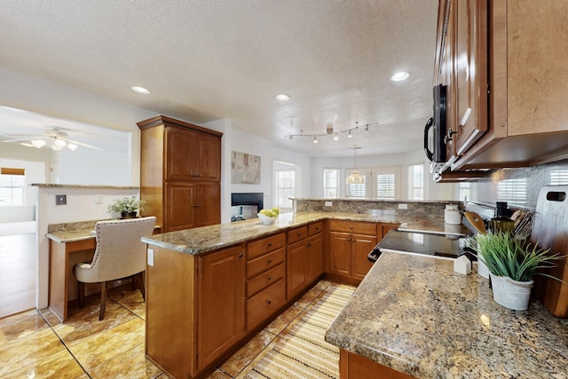 kitchen with light stone counters, pendant lighting, brown cabinets, tasteful backsplash, and a peninsula