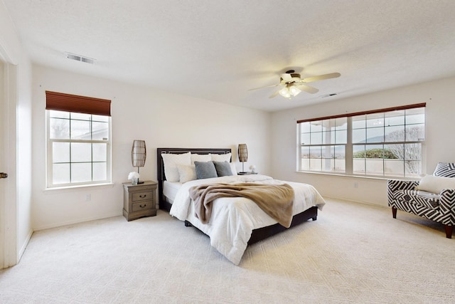 bedroom featuring visible vents, light carpet, and multiple windows