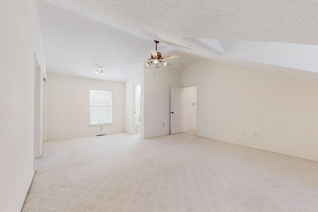 additional living space featuring lofted ceiling, ceiling fan, a textured ceiling, and light colored carpet