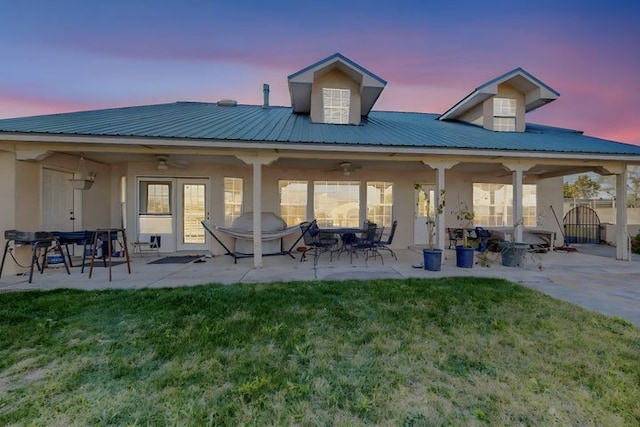 back of house featuring a ceiling fan, a patio area, a lawn, and stucco siding