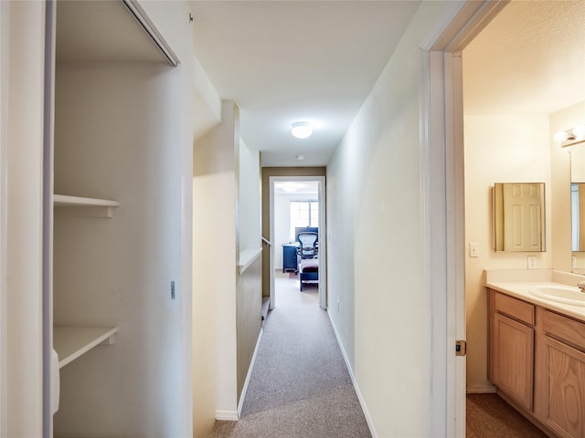 corridor featuring sink and light carpet