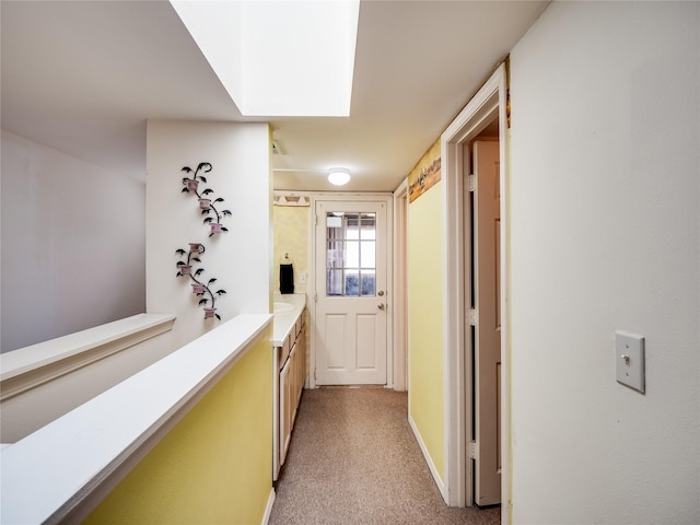 corridor featuring a skylight and light colored carpet