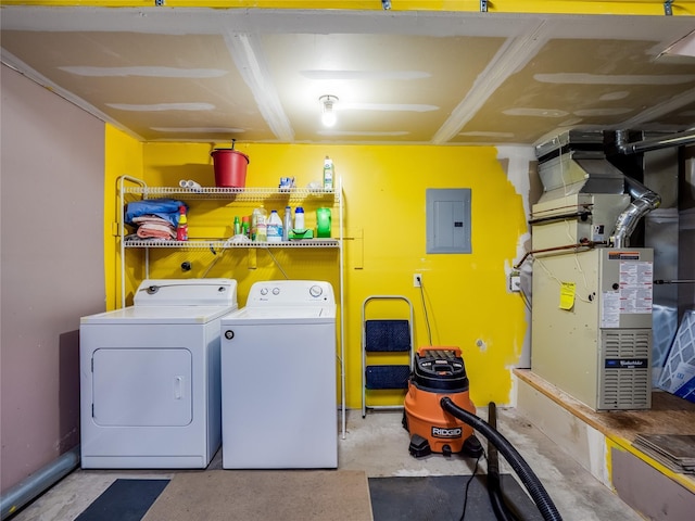 laundry room featuring electric panel, washing machine and clothes dryer, and heating unit