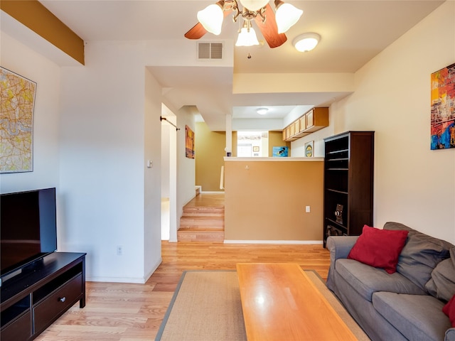 living room with light wood-type flooring, ceiling fan, and a barn door