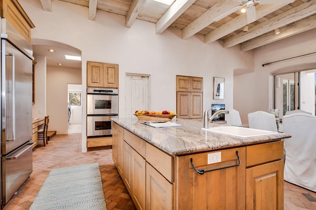 kitchen with wooden ceiling, a kitchen island with sink, appliances with stainless steel finishes, and a sink