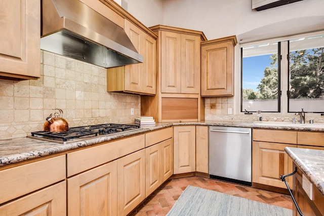 kitchen featuring stainless steel appliances, range hood, light stone counters, and light brown cabinetry