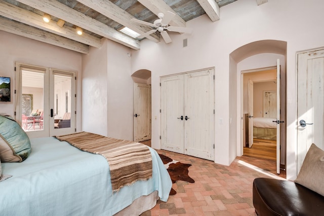 bedroom featuring brick floor, arched walkways, beam ceiling, and french doors