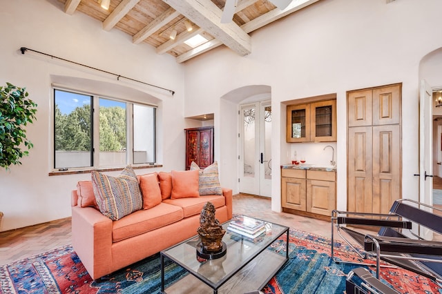 living area featuring wood ceiling, a high ceiling, arched walkways, and beamed ceiling