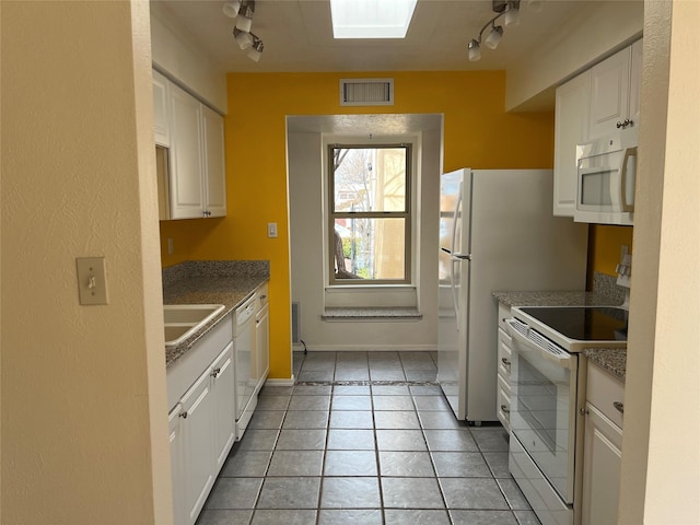 kitchen featuring white appliances, a skylight, a sink, visible vents, and white cabinets