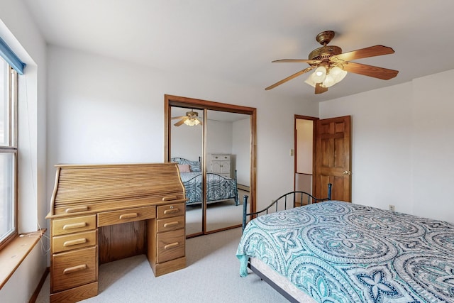 bedroom with light carpet, multiple windows, a closet, and a ceiling fan