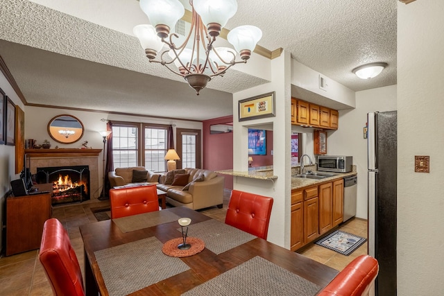 dining area with a textured ceiling, visible vents, a tiled fireplace, and ornamental molding