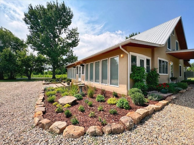 view of side of property with a standing seam roof, metal roof, and stucco siding