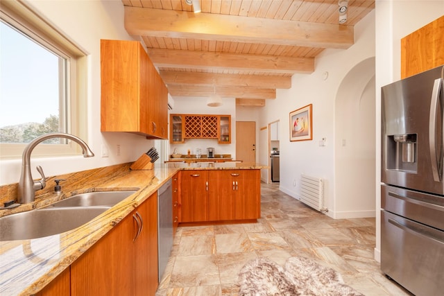 kitchen featuring stainless steel appliances, brown cabinets, glass insert cabinets, and a sink