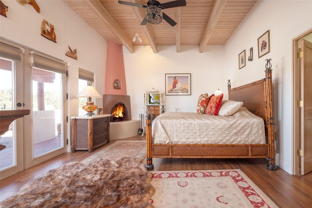 bedroom featuring a large fireplace, wood ceiling, access to outside, dark wood-style floors, and beamed ceiling