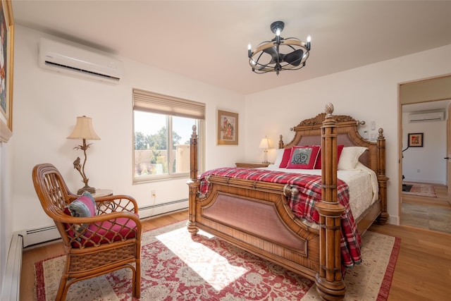 bedroom with light wood-style flooring, a baseboard heating unit, and an AC wall unit