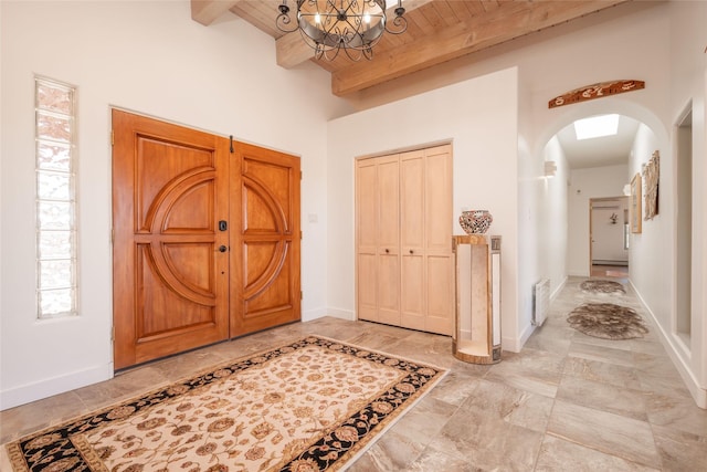 entryway with arched walkways, wood ceiling, baseboards, beam ceiling, and an inviting chandelier