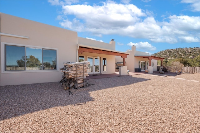 back of house featuring a chimney, a patio, fence, and stucco siding