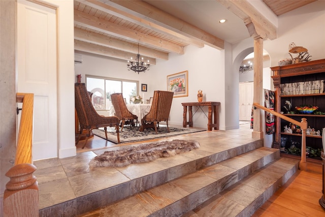 sitting room featuring arched walkways, wooden ceiling, an AC wall unit, beam ceiling, and an inviting chandelier