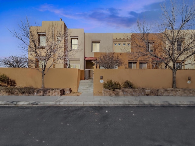 adobe home featuring a fenced front yard and stucco siding