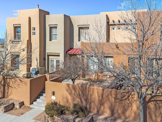 pueblo revival-style home with a fenced front yard and stucco siding