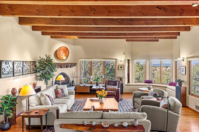 972 Indian Ridge Rd, Santa Fe, NM 87501 - living room featuring a lit fireplace, a high ceiling, beamed ceiling, and light wood-type flooring