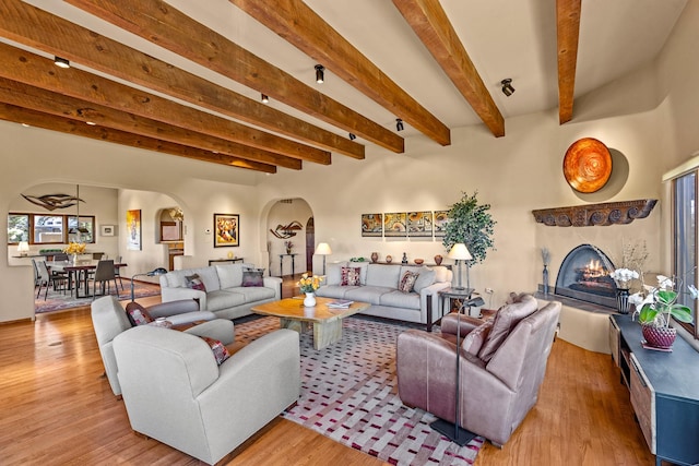 972 Indian Ridge Rd, Santa Fe, NM 87501 - living room featuring light wood-style floors, a premium fireplace, arched walkways, and beamed ceiling