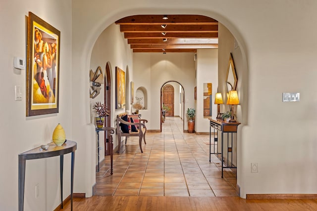 972 Indian Ridge Rd, Santa Fe, NM 87501 - corridor featuring baseboards, arched walkways, beamed ceiling, and light tile patterned flooring