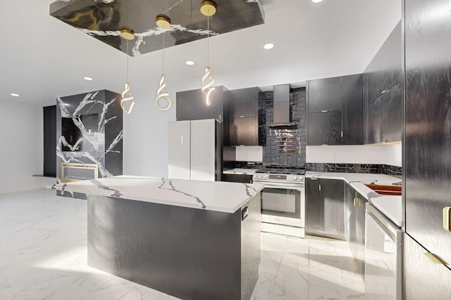 kitchen featuring stainless steel gas range oven, marble finish floor, freestanding refrigerator, wall chimney exhaust hood, and decorative light fixtures