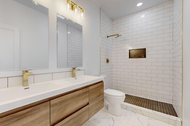 full bathroom with marble finish floor, double vanity, toilet, a sink, and a tile shower