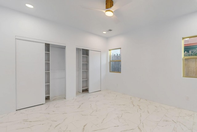 unfurnished bedroom featuring marble finish floor, recessed lighting, a ceiling fan, and multiple closets