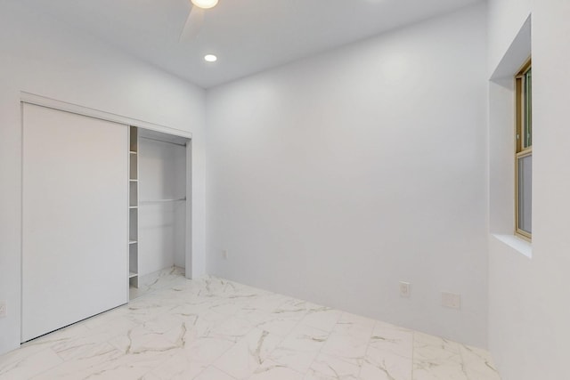 unfurnished bedroom featuring marble finish floor, a ceiling fan, a closet, and recessed lighting