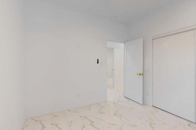 unfurnished bedroom with a closet and marble finish floor