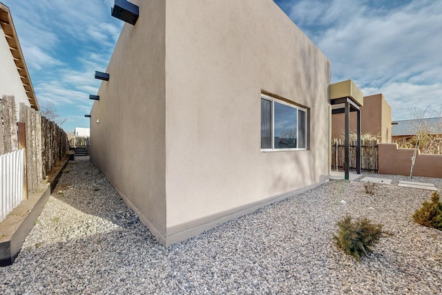 view of side of property featuring a fenced backyard and stucco siding