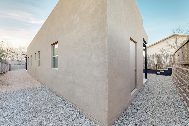 view of home's exterior with fence and stucco siding