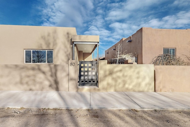 view of side of home featuring a fenced front yard, a gate, and stucco siding