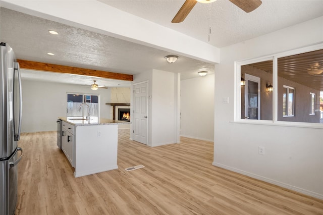 kitchen with stainless steel appliances, a center island with sink, a textured ceiling, and a sink