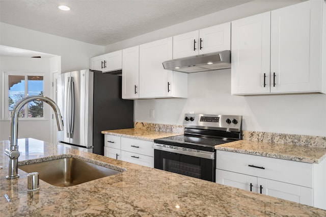 kitchen featuring a textured ceiling, under cabinet range hood, stainless steel appliances, a sink, and white cabinetry