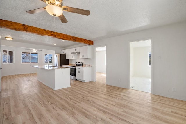 kitchen with stainless steel appliances, a kitchen island, white cabinets, open floor plan, and light countertops