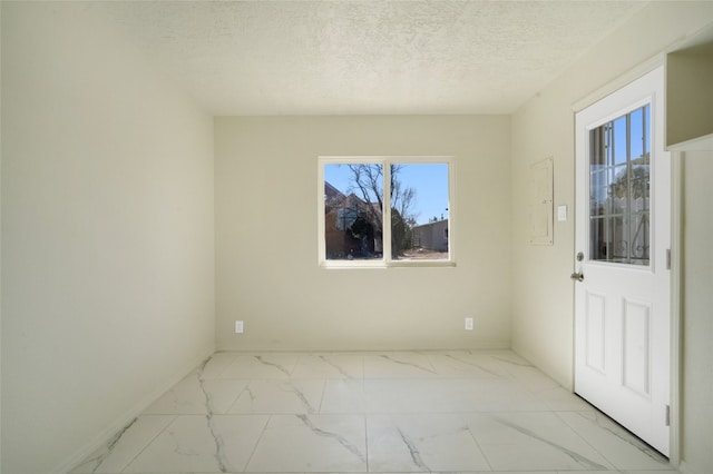 unfurnished room featuring a textured ceiling, marble finish floor, and baseboards