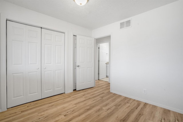 unfurnished bedroom with a textured ceiling, light wood finished floors, visible vents, and baseboards