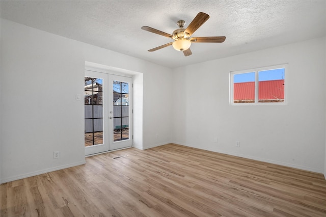 empty room with baseboards, a ceiling fan, a textured ceiling, french doors, and light wood-type flooring